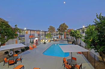 View of soothing swimming pool with orange patio furniture at twiligjht at Allora Phoenix in Phoenix, AZ